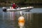 Large white seagull bird standing on bright orange buoy floating in lake with water reflection. Number 8 on the side marking