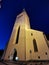 The large white St. Olaf Baptist Church on one of the streets of Old Tallinn against a dark blue sky. Spring evening