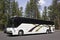 Large White Tour Bus In Forest Parking Lot
