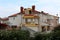 Large white and yellow Mediterranean villa with multiple balconies on each side surrounded with fig trees and other garden