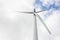 Large wind turbine with white blades on a gray pole isolated on background of the cloudy blue sky