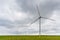 Large wind turbines with blades in the wind park on the background cloudy sky