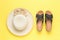 A large women`s hat and black summer sandals on a yellow background. Minimal summer concept