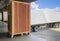 Large Wooden Crate Loading into Shipping Cargo Container. Truck Parked Loading at Dock Warehouse. Supply Chain Shipment Logistics.