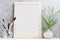 Large wooden Photo frame mock up with green palm leaves in vase and brushes in glass on shelf. Scandinavian style