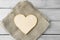 Large wooden pure heart on coarse of cloth on light wooden table. Monochrome beige image