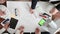 Large work table on which are glasses, phone, markers, pencils, rulers. Hands of designers make amendments to the