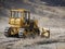 A large yellow bulldozer flattens a mountain dirt road in clouds of dust on a Sunny autumn day