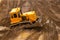 Large yellow caterpillar industrial tractor, iron dump shifts sand and ground, lines road for transport inside development of