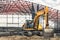A large yellow crawler excavator at a construction site. Construction of a modern frame shop. excavation. Rental of construction
