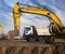 large yellow crawler excavator and a gray dump truck stand at a construction site