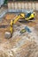 A large yellow excavator digs a foundation pit at a construction site