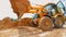 A large yellow excavator is driving on a construction site. Excavator wheels close up