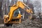 A large yellow excavator stands in the middle of the street