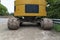 A large yellow excavator visible from the rear, standing on concrete.