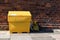 Large yellow grit salt container on pavement sidewalk