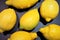 Large yellow lemons of different shapes on a black graphite