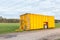 Large yellow manure tank standing in meadow