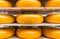 Large yellow rounds of gouda cheese closeup on shelves ready for
