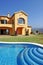 Large yellow sunny spanish villa with pool and blue sky