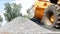 Large yellow tractor loader collects small gravel in the bucket, close-up, loader and small gravel