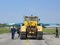 Large yellow tractor transporting military fighter on the runway