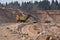 Largest mining excavator with electric shovel loading sand into dump truck in opencast. Orange mining trucks transports sand in