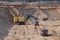 Largest mining excavator with electric shovel loading sand into dump truck in opencast. Orange mining trucks transports sand
