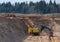 Largest mining excavator with electric shovel loading sand into dump truck in opencast. Orange mining trucks transports sand in