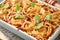 Lasagna. Homemade lasagna pasta rotolo bake with tomato sauce, cream cheese and basil on white skillet on dark slate, stone or