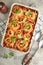 Lasagna. Homemade lasagna pasta rotolo bake with tomato sauce, cream cheese and basil on white skillet on light slate, stone or