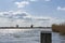 The last mooring post of a boat dock in the lake de Rottemeren with the windmill Tweemanspolder nr 4 in the background on a sunny