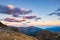 Last warm sunlight on alpine valley with glowing mountain peaks and scenic clouds. Italian French Alps, summer travel destination.