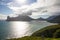 Late afternoon sun reflecting in ocean with beautiful mountain ranges and clouds