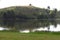 Late afternoon sunlight catches the tree tops beside a peaceful country dam