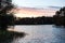 Late evening photo of small countryside pond with trees around on sunset