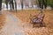 Late fall. An old shabby bench among the fallen leaves by the path on a fog