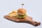 Lateral Hero Shot of a grilled chicken slider burger, fries on a wooden platter board, on a minimal white background with a