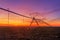 Lateral move agricultural irrigation system on plowed field in sunset