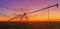 Lateral move agricultural irrigation system on plowed field in sunset