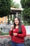 Latin adult woman enjoys a relaxed afternoon walking through the park while having a currant flavored shaved ice drink