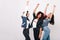 Latin, african and asian girls standing in the same pose with smile and hands up. Indoor portrait of international