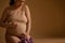 Latin American beautiful gravid woman, expectant mother putting her hands on her pregnant belly, isolated beige backdrop