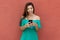 Latin american influencer posting message online with mobile phone with wall as copy space