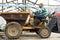 Latin american male farmer driving a mini dump truck, drives out to throw out the weeds.