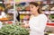 Latin american woman choosing green string bean in supermarket