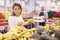 Latin american woman choosing sweet bananas in supermarket
