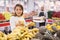 Latin american woman choosing sweet bananas in supermarket