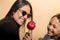 Latin brunette hair mother and daughter enjoying together eating a red caramel apple. Latin woman wear sunglasses