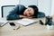 Latin businesswoman sleeping at workplace near notebook and smartphone with blank screen